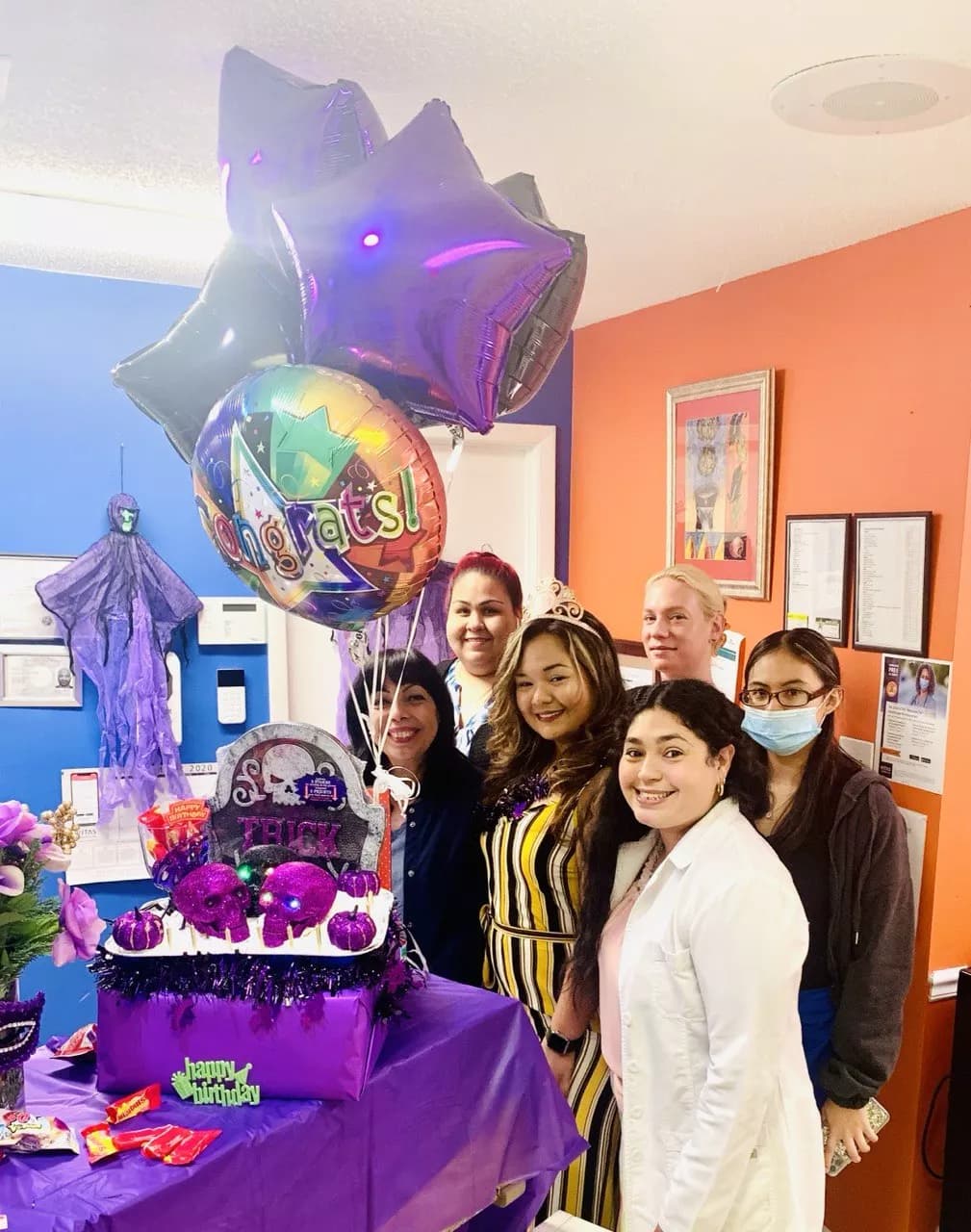 Team members celebrating with balloons and a cake in the office